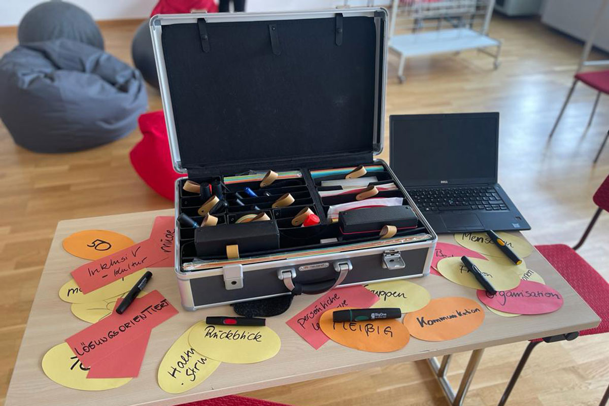 Ein geöffneter Koffer mit Papieren und Stiften.